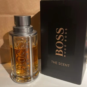 Hugo Boss The Scent 100ml stora flaskan - Säljer en elegant parfym från Hugo Boss, The Scent. Flaskan har en stilren design med metalliska detaljer och en gyllene vätska. Förpackningen är svart med guldtext. Perfekt för den som vill ha en sofistikerad doft. Ny pris är 1500 för 100ml flaskan mitt pris är 899kr för dem 70ml som är kvar. Priset är ej hugget i sten kom med bud (rimliga)