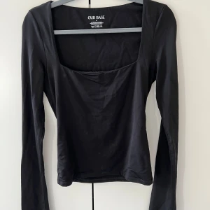 Svart långärmad topp från Our Base - Säljer en stilren svart långärmad topp från Our Base. Toppen har en enkel design med en fyrkantig halsringning och är perfekt för en minimalistisk look.