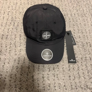 Svart keps från Stone Island - Hej!  Säljer helt ny Stone Island keps som jag har aldrig använt. Vid frågor eller funderingar skriv gärna pm. Tar emot Swish eller kontakt. OBS: SKICKAS EJ! Bara avhämtning i Göteborgsområdet.