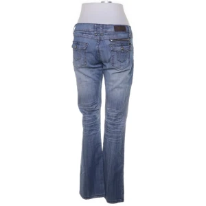 Blå bootcut jeans - Snygga blå bootcut jeans med klassisk femficksdesign och subtila slitningar. Jeansen har en lågmidjad passform och stängs med dragkedja, obs knappen har åkt av. Perfekta för en avslappnad stil.