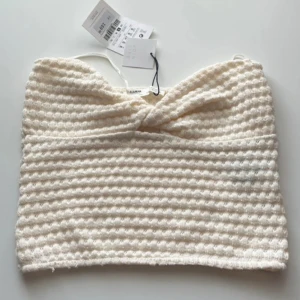  ribbad tubtopp från Pull&Bear - Säljer en snygg vit ribbad tubtopp från Pull&Bear. Toppen har en stilren design med en twistdetalj framtill som ger en unik touch. Perfekt för att styla med olika outfits. Ny med taggar kvar!