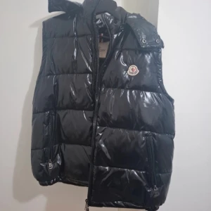 Moncler väst svart - Säljer denna feta Moncler väst i färgen svart då den blivit för liten för mig. Västen är bara använd ett fåtal gånger, och är i nyskick. Passar perfekt till våren! 