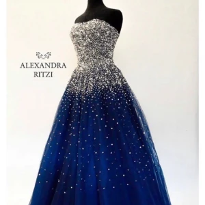 Klänning från Alexandra Ritzi - Säljer en fantastisk blå axelbandslös klänning från Alexandra Ritzi. Klänningen är dekorerad med glittriga detaljer som ger en magisk känsla. Perfekt för en speciell kväll!