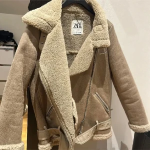 Beige jacka från Zara - Säljer en snygg beige jacka från Zara med mjukt foder och dragkedja. Jackan har en klassisk design med bälte och långa ärmar, perfekt för kyligare dagar. Den har en stilren look med detaljer som ger extra karaktär.🩷