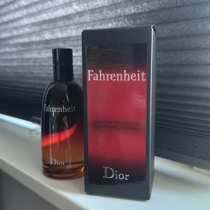 Fahrenheit Eau de Toilette från Dior ( 100% äkta ) - Säljer en flaska Fahrenheit Eau de Toilette från Dior. Flaskan har en elegant design med en övergång från svart till röd. Parfymen kommer i en matchande svart och röd kartong. Perfekt för den som söker en klassisk och tidlös doft.