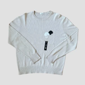 White Sweatshirt With Spades - Snygg beige tröja med ett diskret svart spade på bröstet. Tröjan har en klassisk rund hals och långa ärmar, perfekt för en stilren look. Passar både till jeans och mer dressade byxor.