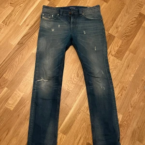 Blå Diesel Jeans - Snygga blå jeansbyxor från Diesel med en slim fit. De har en klassisk femficksdesign och slitna detaljer för en trendig look. Perfekta för en avslappnad stil. Köpte för 1300 säljer för 500:)