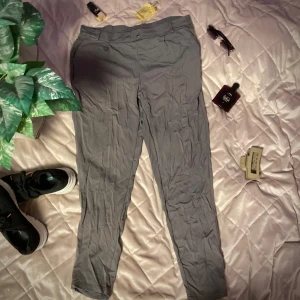 Grå mjukisbyxor - Snygga grå byxor med en stilren design och knappdetalj i midjan. Perfekta för en avslappnad look. De har en rak passform och är tillverkade i ett bekvämt material. 