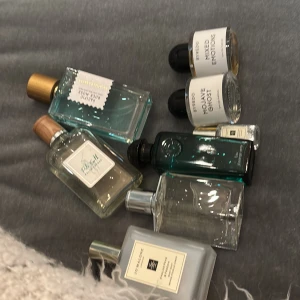 Samling av parfymer - En samling av olika parfymer med varierande flaskdesign och färger. Inkluderar flaskor med både genomskinliga och färgade glas, samt lock i olika stilar. Perfekt för den som vill ha ett brett urval av dofter att välja mellan.