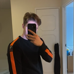 Svart tröja från Parajumpers - Säljer en svart tröja från Parajumpers med orange ränder längs ärmarna. Storlek Y-M, passar mig väldigt bra, jag är 173 cm. Pris kan diskuteras!!!