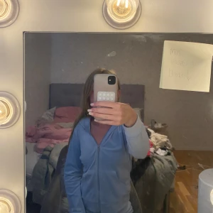 Ljusblå velourhoodie från Gina Tricot - Supermjuk ljusblå hoodie i velour från Gina Tricot. Tröjan har dragkedja, huva med snörning och två fickor framtill. Perfekt för chill dagar eller när du vill vara extra comfy. Snygg och enkel att matcha med jeans eller mjukisbyxor. Aldrig använd bara testad🥰