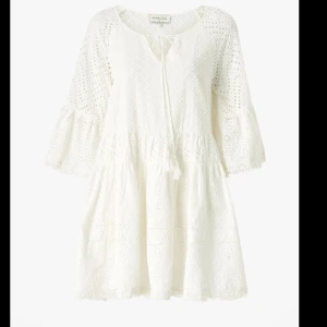 Vit broderad kortklänning från By Malina - Superfin vit kortklänning från By Malina med broderade detaljer och trekvartsärm. Klänningen har knytning vid halsen och är tillverkad i bomull, perfekt för sommarens alla tillfällen. Passar även s/m! Nypris 2000kr