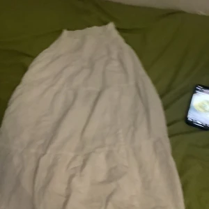 Vit långkjol i bomull - Säljer en vit långkjol i mjuk bomull. Kjolen har en enkel och flowy design som ger en avslappnad vibe. Perfekt för varma dagar när du vill ha något luftigt och stilrent.