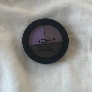 GOSH lila ögonskuggspalett - Snygg ögonskuggspalett från GOSH med två lila nyanser, en ljusare och en mörkare. Kommer i en rund svart dosa med spegel och applikator. Perfekt för att skapa kreativa ögonlooks med lila toner. Aldrig använd!