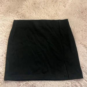 Kjol med slits  - Säljer en svart, stilren kortkjol med rak passform. Kjolen är basic och lätt att matcha med olika outfits. Har även en slits som gör kjolen unik. Är i storlek XS från lager 157. Inga defekter!🌸