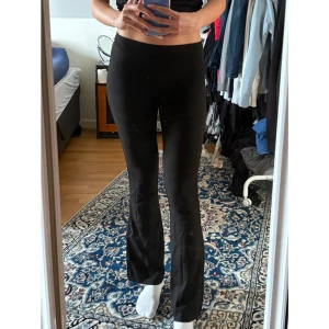 Mid/låga bootcut leggings - Säljer ett par svarta leggings med bootcut som går att has högmidjade till lågmidjade. På mig sitter de mid till low waist då de är små för mig i midjan. De är stretchiga och sitter tight upptill men släpper ut vid bensluten. Bekväma och perfekta både hemma och ute! Säljer då de är för små för mig. Lite korta på mig som är 174 cm.