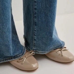 Beige ballerinaskor med rosett från Nelly - Snygga beige ballerinaskor i glansigt syntetmaterial från Nelly. Skorna har rund tå, platt sula och en söt rosettdetalj framtill. Perfekta för dig som gillar en clean och klassisk look med en touch av Paris-vibe. Skorna har inte blivit använda för att de var för små!! Skriv gärna om du har några frågor!!❤️❤️❤️