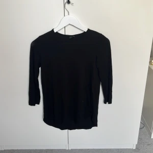 Svart långärmad tröja Gina Tricot XS - Enkel och stilren svart långärmad tröja från Gina Tricot i storlek XS. Tröjan har rund halsringning och är tillverkad i mjuk bomull, perfekt att matcha med jeans eller kjol för en clean look.