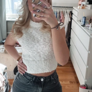 Vit stickad croppad topp Gina Tricot - Superfin vit stickad croppad topp från Gina Tricot. Toppen är ärmlös med hög hals och har en mjuk, lite bubblig struktur. Passar XS också