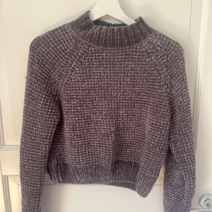 Mörkgrå stickad tröja med hög krage - Supermysig mörkgrå stickad tröja med hög ribbad krage och långärmad modell. Tröjan har en chunky struktur och är perfekt för kyliga dagar. Passar dig som gillar en enkel men ändå trendig look.