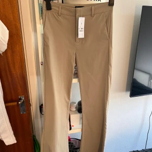 Beiga bootcut kostymbyxor - Snygga beiga kostymbyxor från Gina tricot med bootcut. Midwaist men går även att ha sim low waist. Aldrig använda ❤️‍🔥