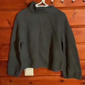 Mörkgrå ribbstickad tröja från C - Säljer en mörkgrå ribbstickad tröja från C i storlek S. Tröjan har hög krage och långa ärmar, perfekt för kyliga dagar. Den är gjord i ett mjukt och skönt stickat material och har en loose passform som ger en avslappnad vibe.