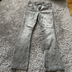 Grå low waist bootcut jeans med fickdetaljer - Snygga grå jeans med bootcut-modell och coola fickdetaljer bak med knappar. Jeansen har klassisk femficksdesign Perfekta för dig som gillar en avslappnad men trendig look. Jeansen är köpta på H&M barnavdelningen i storlek 170. Aldrig använda