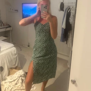 Grön blommig klänning med slits - Superfin grön klänning med vita blommor och smala axelband samt slits🥰