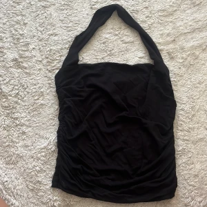 Svart bandeau topp från Gina Tricot - Säljer en svart bandeau topp från Gina Tricot med breda axelband och åtsittande passform. Toppen är ärmlös och har en enkel, stilren design som är lätt att matcha. Perfekt för dig som gillar minimalistisk stil och vill ha något bekvämt och snyggt.