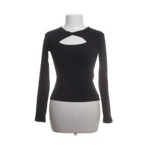 Svart långärmad topp med cut out - Svart långärmad topp från Gina tricot med snygg cut out-detalj vid halsen. Figurnära passform som ger en stilren och trendig look. Perfekt att matcha med jeans eller kjol för en cool outfit.