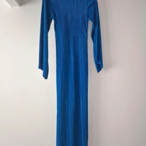 Blå långklänning från Boohoo - Snygg blå långklänning från Boohoo med långärmad design och coolt ribbat tyg. Klänningen har en smickrande rak passform och är perfekt för dig som vill sticka ut med färg. Materialet känns lätt och följsamt.