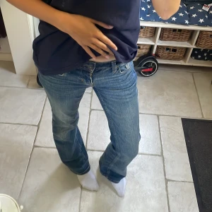 Blå bootcut jeans med fickdetaljer - Snygga blå jeans med bootcut passform och låg midja. Jeansen har bakfickor med lock och knapp. Köpa på HM för ett bra tag sedan! Storlek 34.
