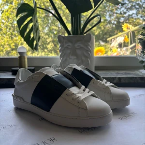 Valentino Garavani Open sneakers vit/blå - Säljer dessa trendiga valentino skor som tyvärr har slutat passa. Skorna är i färgen mörkblå och är i ett väldigt gott skick,  har en liten repa på den vänstra skon som knappast syns. 