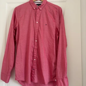 Rosa slim fit skjorta Tommy Hilfiger - Snygg rosa skjorta från Tommy Hilfiger i slim fit-modell med stretch. Klassisk button down-krage, vita knappar och diskret logga på bröstet. Skjortan är långärmad och tillverkad i bomullsmix för en bekväm känsla. Perfekt för dig som gillar stilrena plagg med en modern touch.