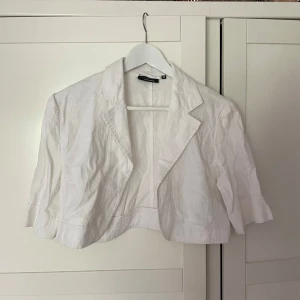 Vit croppad kavaj från Woman by Halens - Vit croppad kavaj från Woman by Halens i linne. Jackan har klassisk krage, trekvartsärmar och en stilren look som passar perfekt till jeans eller kjol.