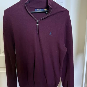 Vinröd half zip tröja Polo Ralph Lauren - Vinröd långärmad tröja från Polo Ralph Lauren med half zip-dragkedja och broderad logga på bröstet. Tröjan är stickad och har en klassisk, stilren look som passar perfekt till lager-på-lager. Materialet är mjukt och bekvämt. Säljer pågrund av att jag ej använder den längre 