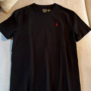Svart t-shirt från Ralph Lauren - Svart t-shirt från Polo Ralph Lauren med klassisk passform. T-shirten har korta ärmar och är tillverkad i mjuk bomull. Skick: 10/10. Fraktar inom 1 dag, Mvh