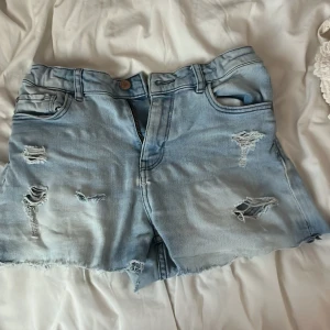 Ljusblå lågmidjade jeansshorts - Säljer ett par ljusblå jeansshorts med slitna detaljer. Använda några gånger, men ändå fint skick! Hör av er vid frågor, pris går att diskutera!💕