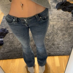 Blå bootcut jeans låg midja - Säljer ett par blå jeans med bootcut och låg midja. Jeansen har klassisk femficksdesign och snygg tvätt med lite slitningar. Perfekta om du gillar en avslappnad men ändå trendig look. Storlek 26, nästan aldrig används💕