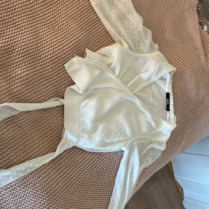 Vit omlottblus från Bik Bok XS - Supersöt vit omlottblus från Bik Bok i storlek XS. Blusen har transparenta, puffiga långärmar, knytband i midjan och små prickar i tyget. Köpte den på Vinted och säljer nu för den är för liten. Blusen är trendig och perfekt för sen sommaren.