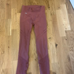 Rosa seamless leggings Aim'n S - Säljer ett par seamless leggings från Aim'n i en snygg dammrosa färg. De har hög midja med ribbad linning och ventilerande detaljer längs benen. Materialet är stretchigt och passar perfekt för träning eller chill. Supersköna och sitter på plats hela dagen. Knappt använda