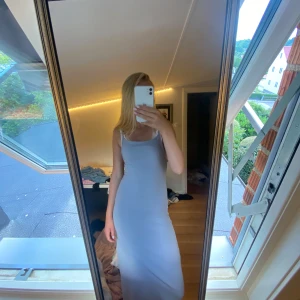 Ljusgrå långklänning med smala axelband - En stilren och enkel ljusgrå långklänning med smala axelband och rak passform. Klänningen är ärmlös och har en mjuk, följsam känsla som sitter snyggt mot kroppen. Perfekt för dig som gillar minimalistisk och clean stil. Kan diskutera pris🥰