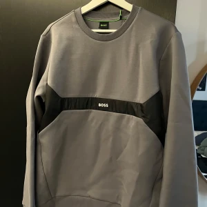 Boss sweatshirt grå  - Grå Sweatshirt från Boss. Enkel och bekväm tröja. Helt oanvänd, den har kvar box och tags. Storleken är M. Bara att höra av sig med frågor och funderingar.