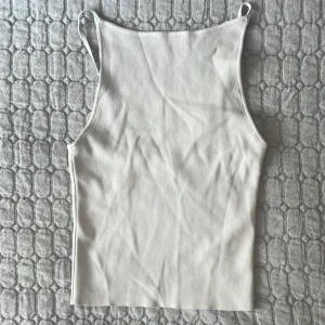 Ljusgrå ribbad linnetopp med smala band - Säljer en stilren ljusgrå linnetopp med smala axelband och rak halsringning. Toppen är ribbad och har en tight passform som sitter snyggt på kroppen. Perfekt att matcha med jeans eller kjol för en clean look.🧡