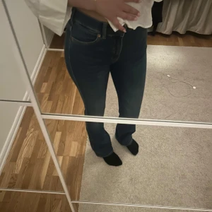 Blå bootcut jeans - Snygga blå bootcut jeans med mid waist  och klassisk femficksdesign. Perfekta för en avslappnad stil med en touch av retro. Passar bra till både sneakers och klackar. (Helt oanvända för att det är tyvärr för långa)