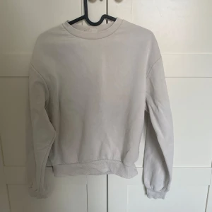 Vit sweatshirt - Vit sweatshirt med rund hals och ribbade muddar vid ärmslut och nederkant. 