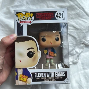 Eleven with Eggos - Cool Funko Pop! vinylfigur av Eleven från Stranger Things, komplett med Eggos och ikonisk outfit. Perfekt för fans av serien och samlare som vill ha något unikt på hyllan. En rolig och stilren detalj för alla som älskar popkultur! Pris kan diskuteras! 