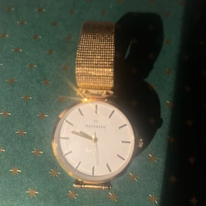 Klocka från Mockberg Livia  - En stilren klocka i fint skick med vit urtavla. Armbandet är i guldig mesh och ger en modern och clean look. Klockan har rund form och spänne med Mockberg-logga. Perfekt accessoar för dig som gillar enkel men snygg design.       Fabrikat	Mockberg  Damklocka Modell	Livia 38 MO501 Diameter (mm)	38 Material armband	Guld/Stål