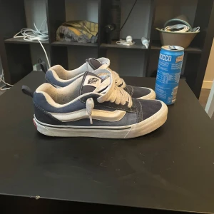 Blå och vita Vans Old Skool sneakers - Säljer ett par klassiska Vans Old Skool sneakers i mörkblått och vitt med den ikoniska sidoremsan. Skorna har vit sula, snörning och ovandel i mocka och canvas. Perfekta för dig som gillar streetstyle och skatekänsla.