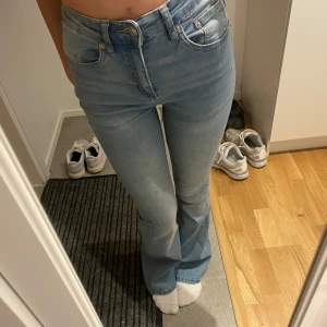 Ljusblå bootcut jeans - Säljer ett par ljusblå jeans med bootcut-modell och klassisk femficksdesign. Jeansen har hög midja och är tillverkade i mjukt denimtyg som sitter snyggt över höfterna och låren innan de släpper ut vid bensluten.
